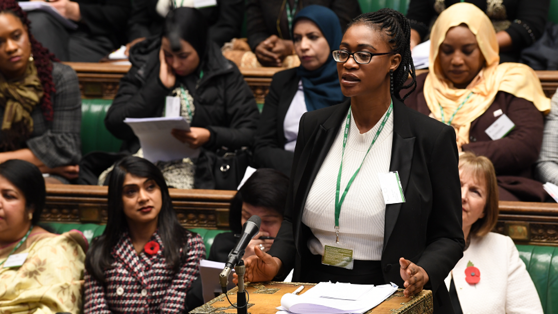 A woman speaking in the midst of other sitting women in the UK Parliament