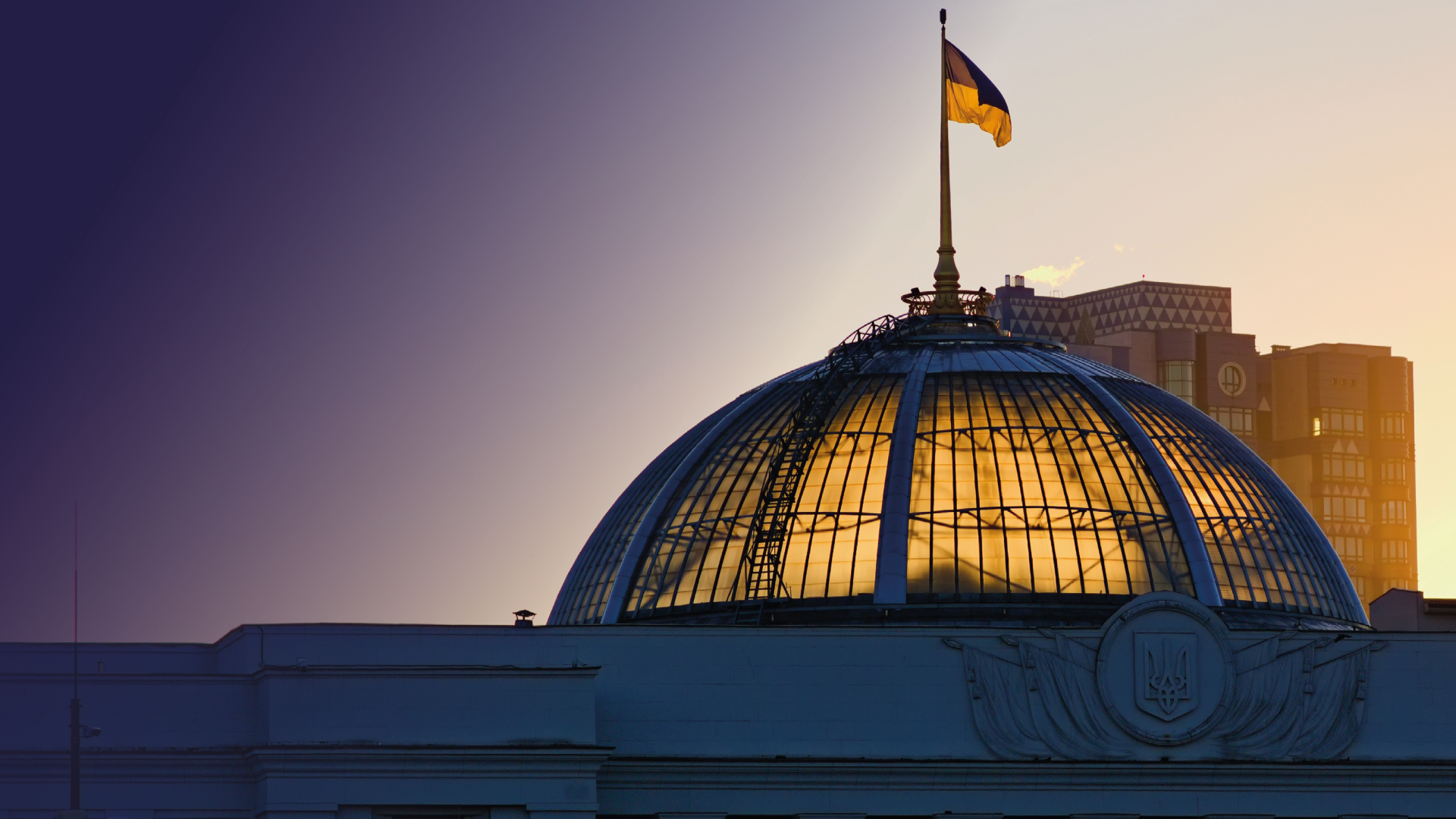 The sun coming through the dome of the Parliament of Ukraine, with the Ukrainian flag flying above 