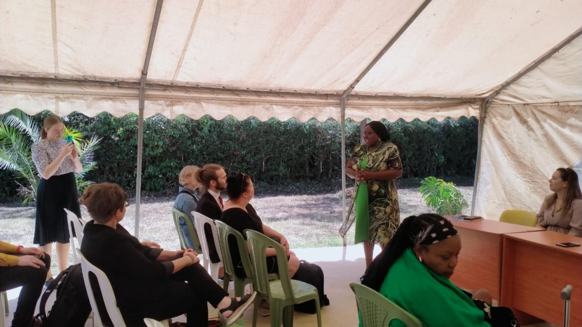 People sitting while another is speaking to them while standing.