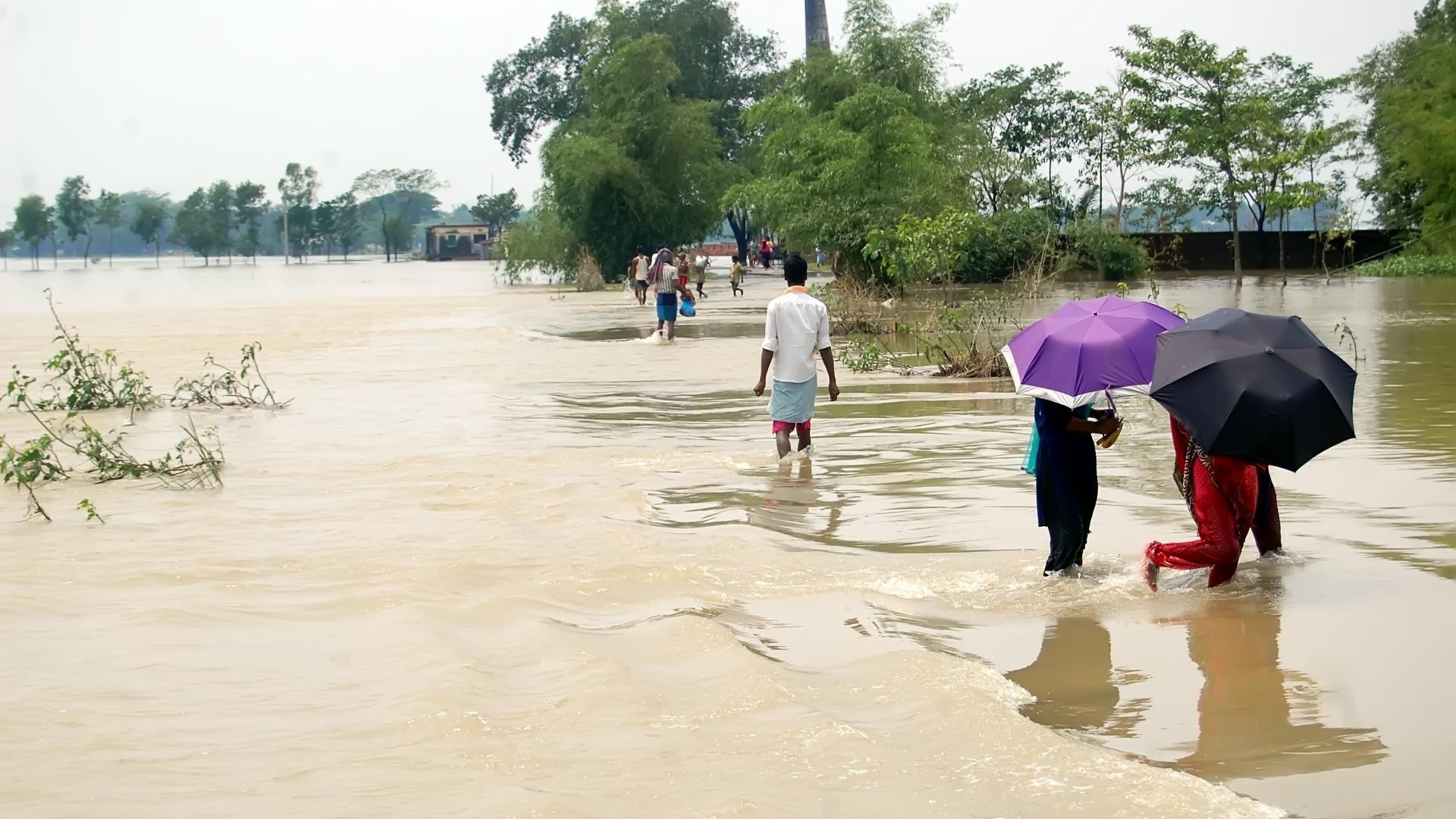 People walking through brown flood waters