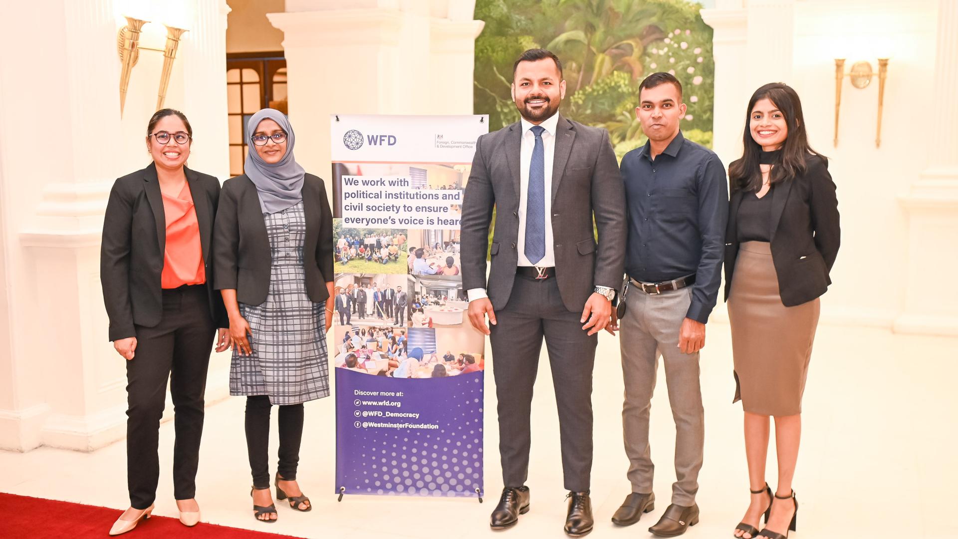 Group of people posing for a picture next to a WFD pull-up banner