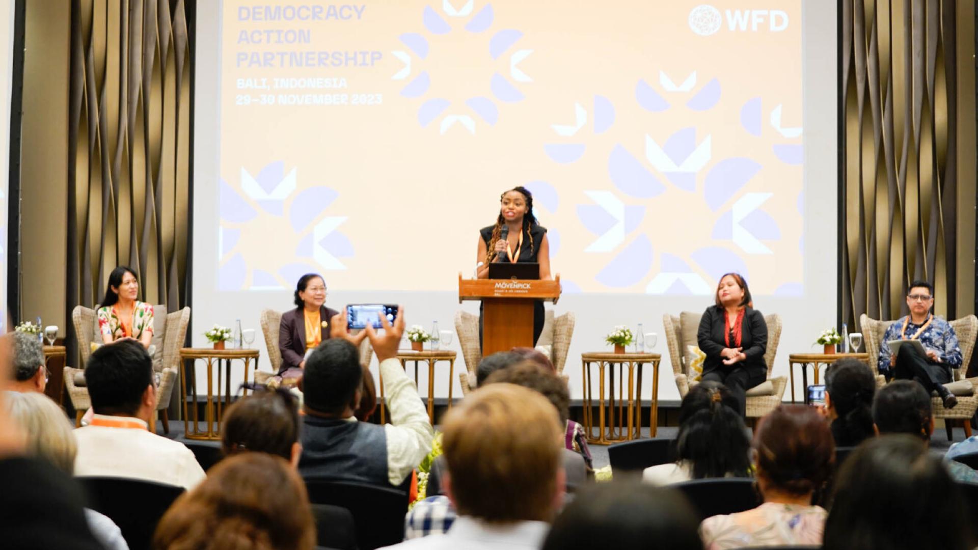 A woman speaking from a podium in front of an audience of people