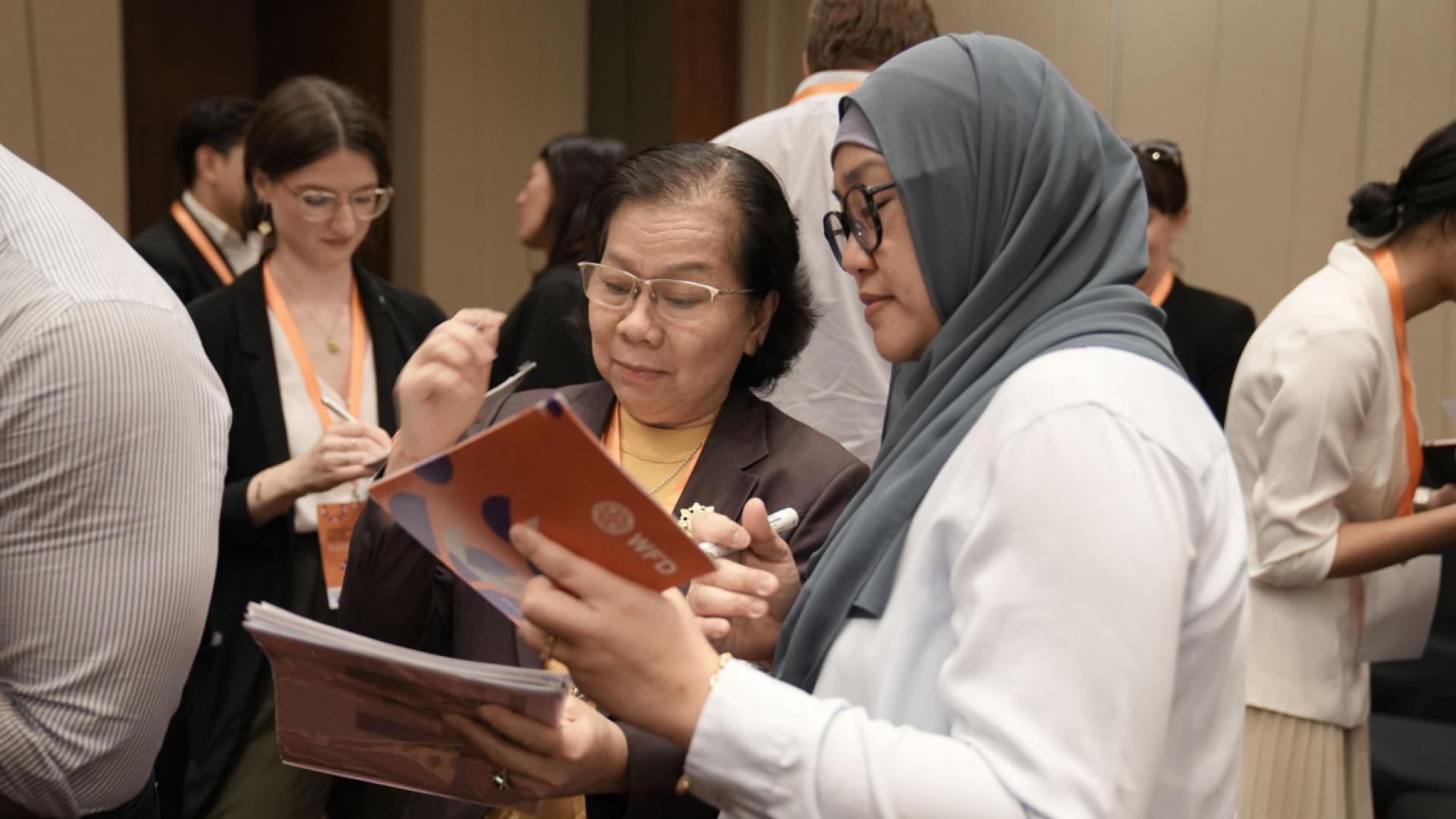 Two women inspecting democracy action partnership materials