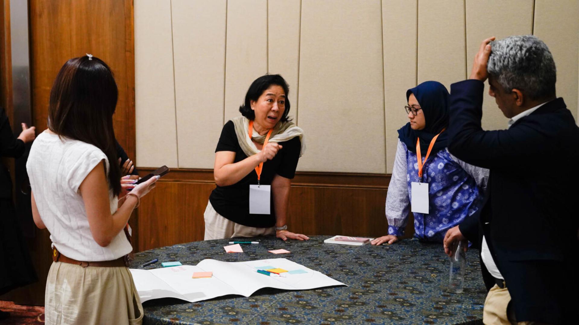 A group of people around a table with a piece of paper on it, discussing