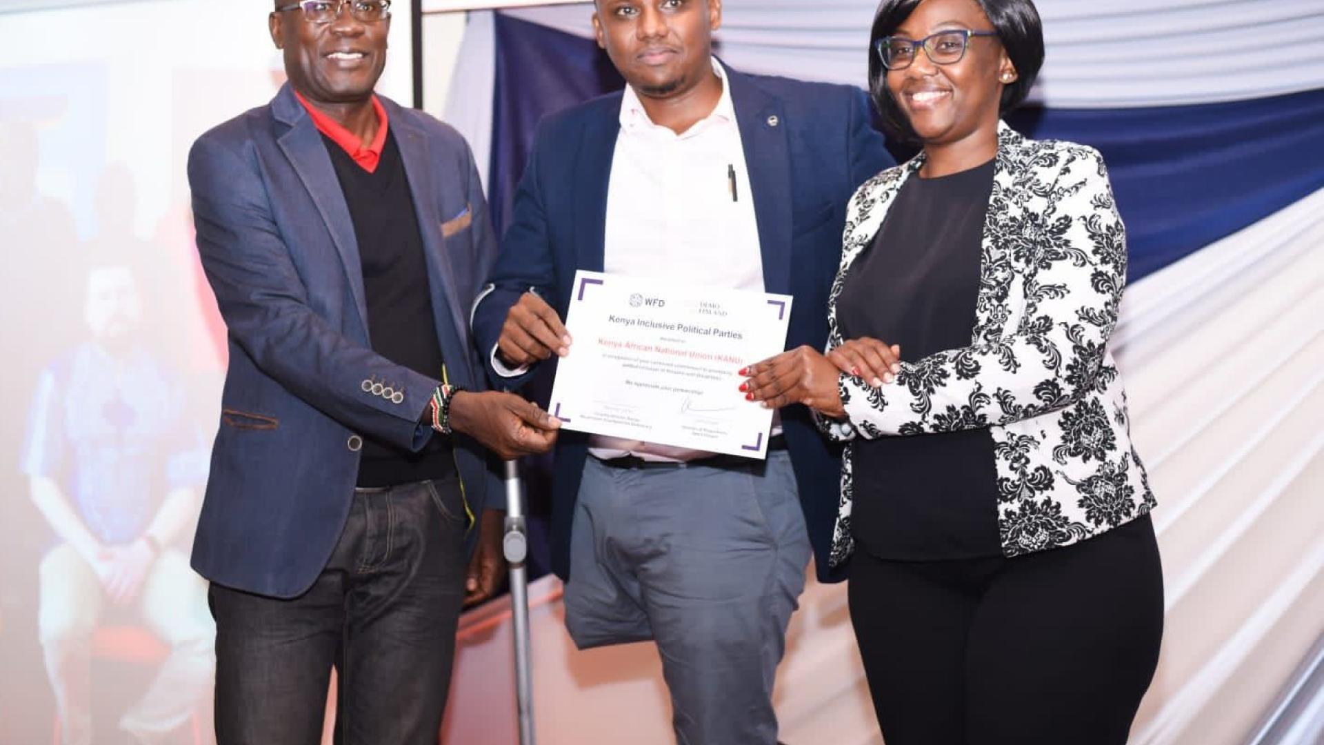 Kenya Office country director, Mrs. Maureen Oduori (right), awarding the Kenya African National Union (KANU) political party officials a certificate in recognition of their continued commitment to strengthening the political inclusion of persons with disabilities during the Kenya Inclusive Political Parties award ceremony in Kenya on December 6.