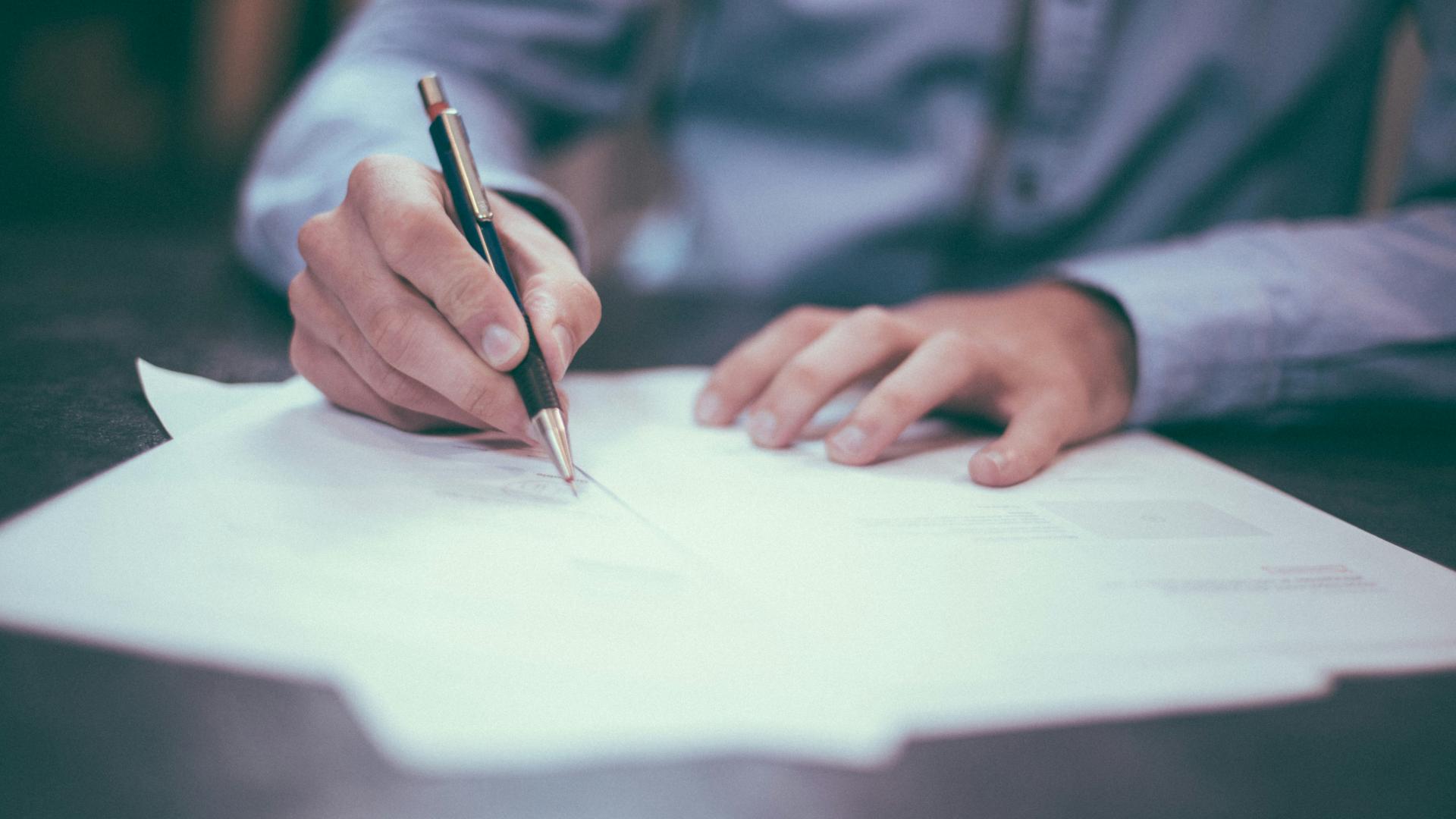 A person wearing grey shirt writing