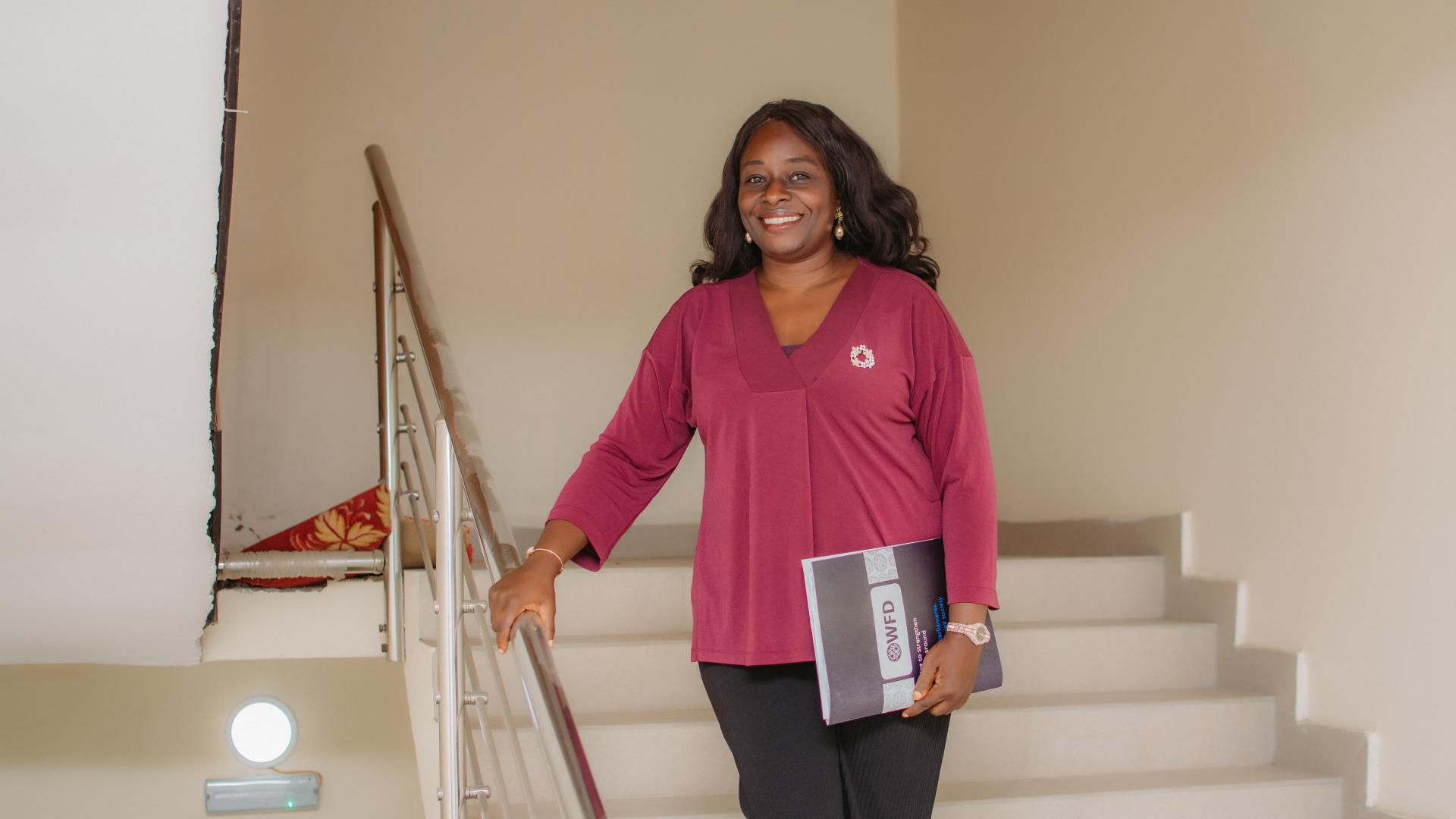 a woman stands on the stairs holding a document