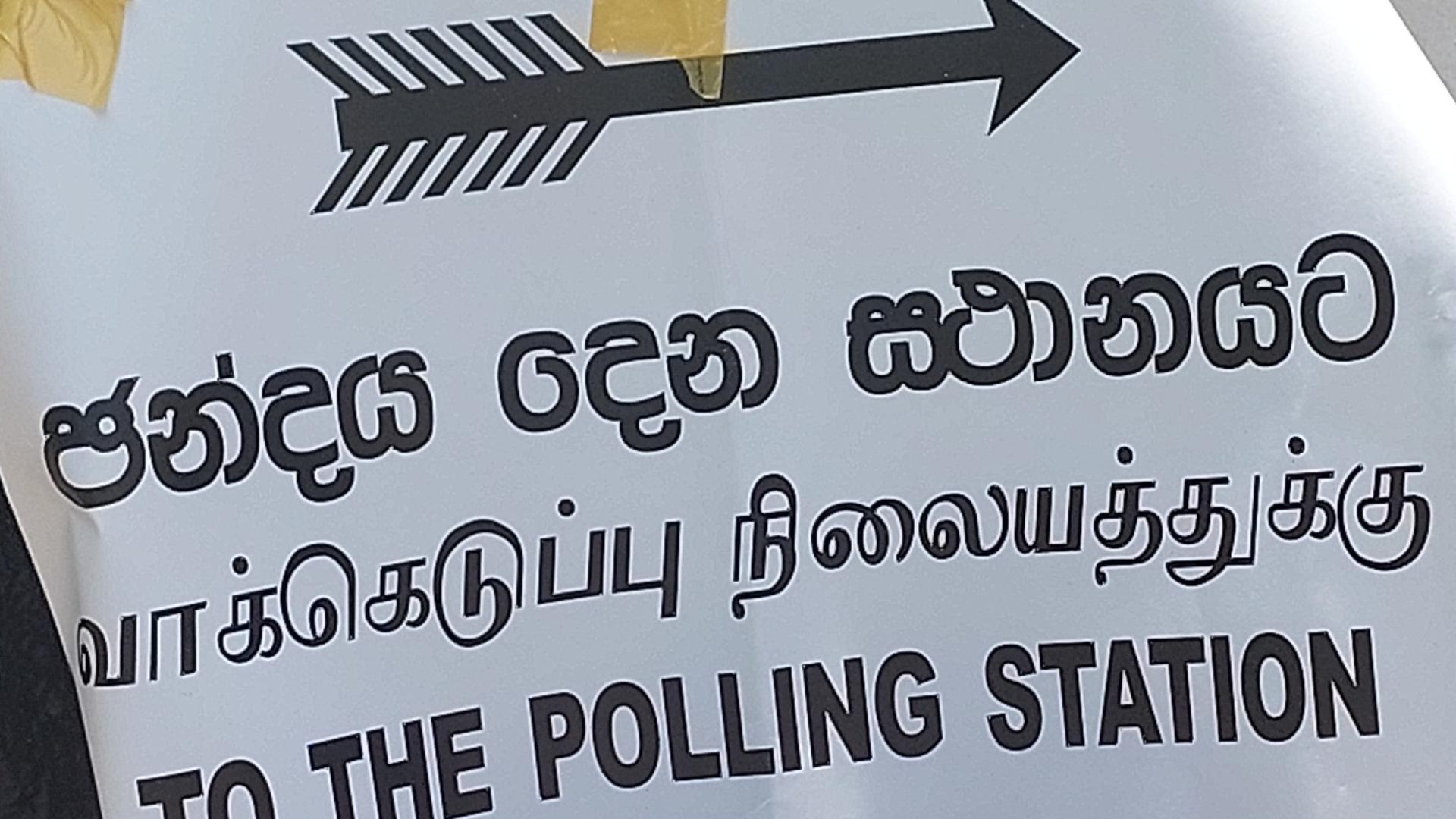 A trilingual sign with an arrow that points to the polling station