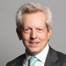 A man in a suit and tie smiling at the camera