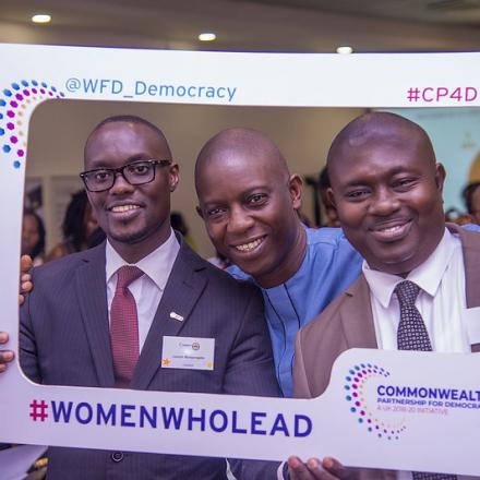 Three men holding up a sign saying women who lead
