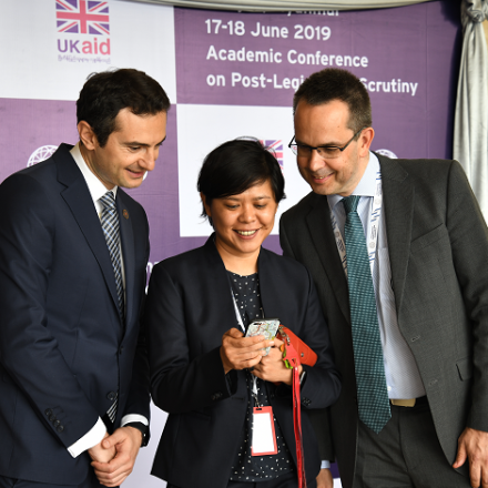 Three people standing together looking at a mobile phone